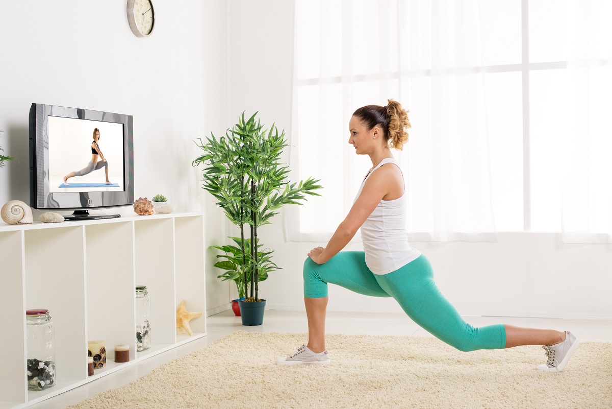 Beautiful young woman stretching out her legs at home in front of the tv